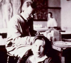 Photograph of Eliel Saarinen working with a young Eero Saarinen sitting on the floor beside him