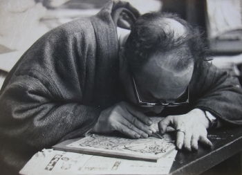 Yoriko Ishii's photograph of Shikō Munakata shows the artist at work on a woodblock.
