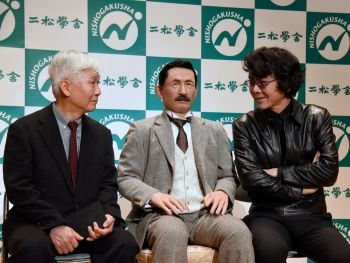 This 2016 <i>Japan Times</i> photograph shows an android, resembling Natsume Sōseki, with the author's grandson on the left and the noted novelist Hiroshige Ishiguro on the right.