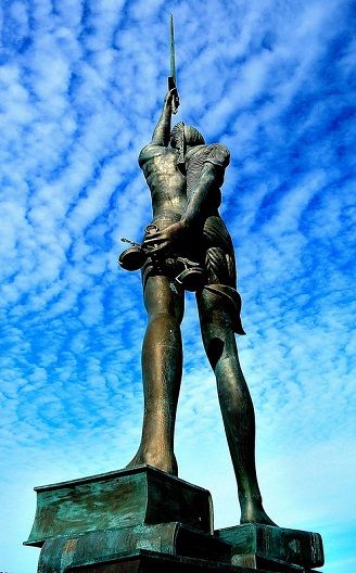Hirst's stainless steel and bronze statue <i>Verity</i> (2012) stands over the harbor in Ilfracombe, Devon, UK. The image of Truth stands 20 meters tall, pregnant, and holding a sword while standing atop of law books. Half of the sculpture displays the anatomy of the woman and her fetus.