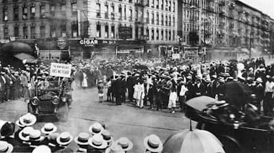 Scene from a Universal Negro Improvement Association parade in Harlem, 1920. A car drives by with a sign that reads “The New Negro Has No Fear.”