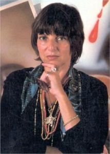 Audrey Flack photographed in the late 1970s, with her painting <i>Marilyn (Vanitas)</i>, (1977) seen in the background