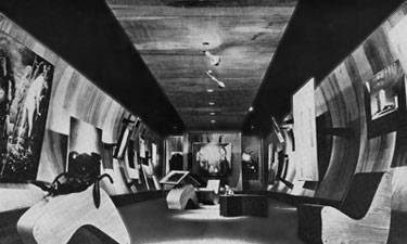 The concave walls of the Surrealist gallery allow the paintings to protrude into the viewer’s space.