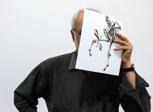 Hans Haacke at the Paula Cooper Gallery hiding his face behind a sketch of <i>Gift Horse</i> (2014). Photographed by Misha Friedman