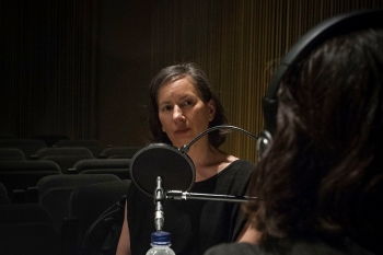 A photograph of Andrea Fraser giving a radio talk at the Museu d'Art Contemporani de Barcelona in 2016.
