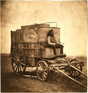 Roger Fenton photographs his colleague Marcus Sparling seated on Fenton's mobile darkroom in Crimea in 1854.