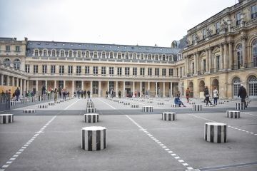 In the inner courtyard of Paris' Palais Royal, where the building's parking lot once sat, French artist Daniel Buren created the site-specific installation <i>Les Deux Plateaux</i> (1985). The work is comprised of 260 black and white striped columns which take root in the basement and emerge from the ground of the courtyard to stand at different heights - creating a sense of rhythm, and contrasting sharply with the classical architecture of the surrounding palace.