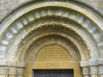 A Norman arch at the center portal of St Michael's and All Angels Church (12th century) with the zigzag molding often used for decorative effect, Gloucestershire, England. Photo by Jongleur.