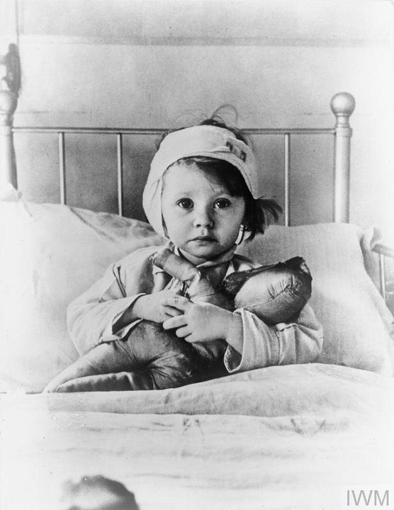 Eileen Dunne, aged three, sits in bed with her doll at Great Ormond Street Hospital for Sick Children, after being injured during an air raid on London in September 1940 (1940)